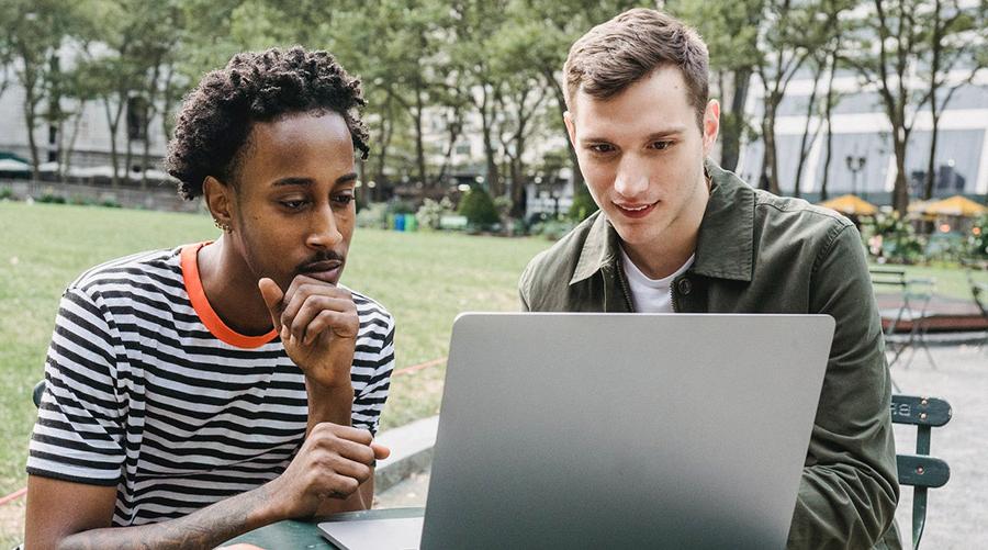 two young men looking at a laptop on campus